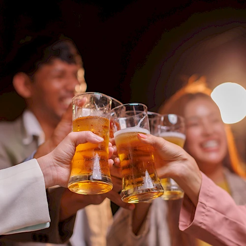 Friends clinking beer glasses in a lively night out, cheers all around at a social gathering.