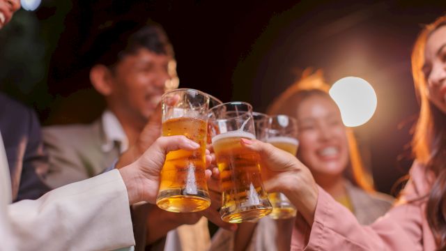 Friends clinking beer glasses in a lively night out, cheers all around at a social gathering.